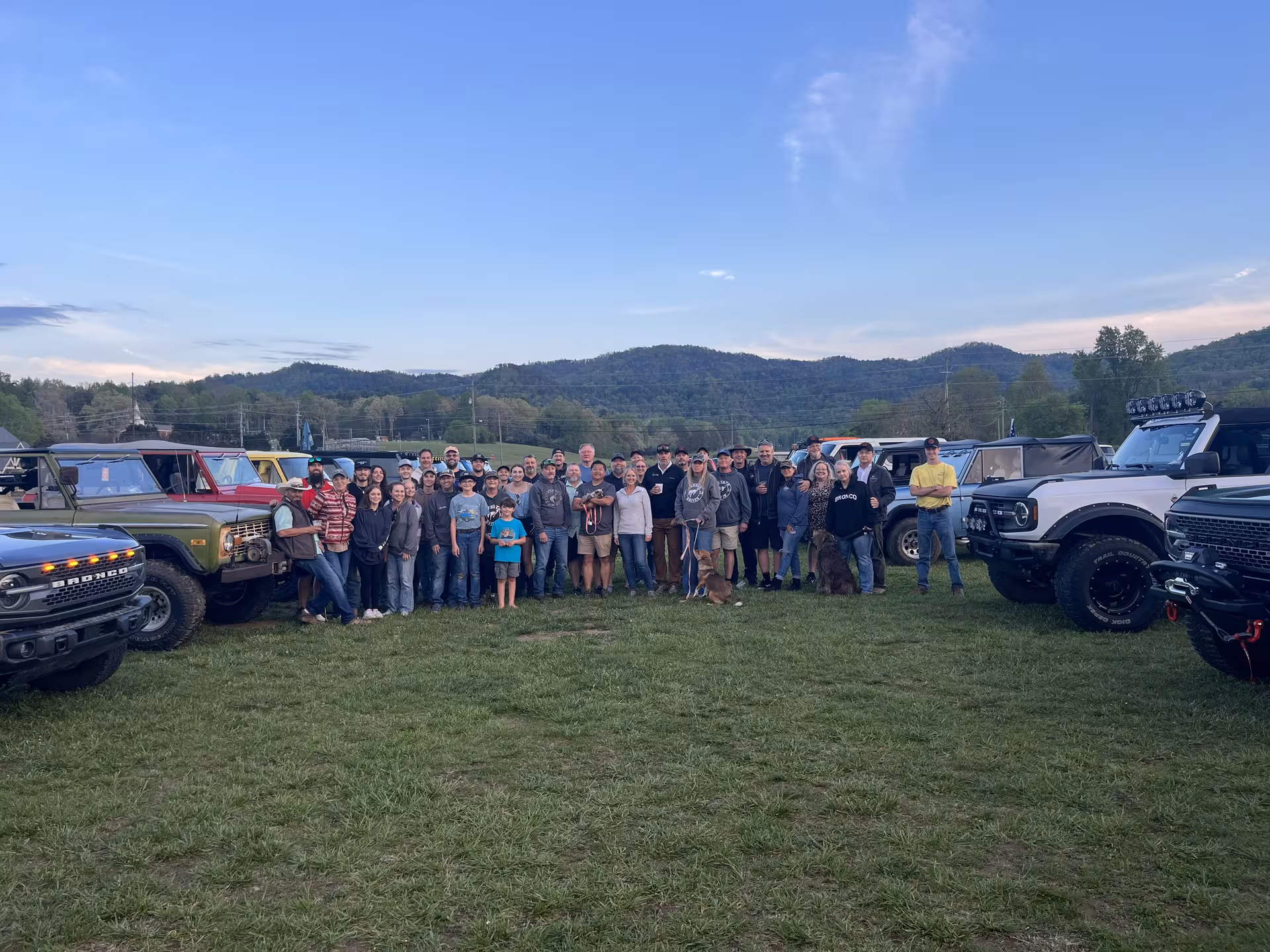 Georgia Broncos members gathered between trucks at a mountain meetup in golden hour light